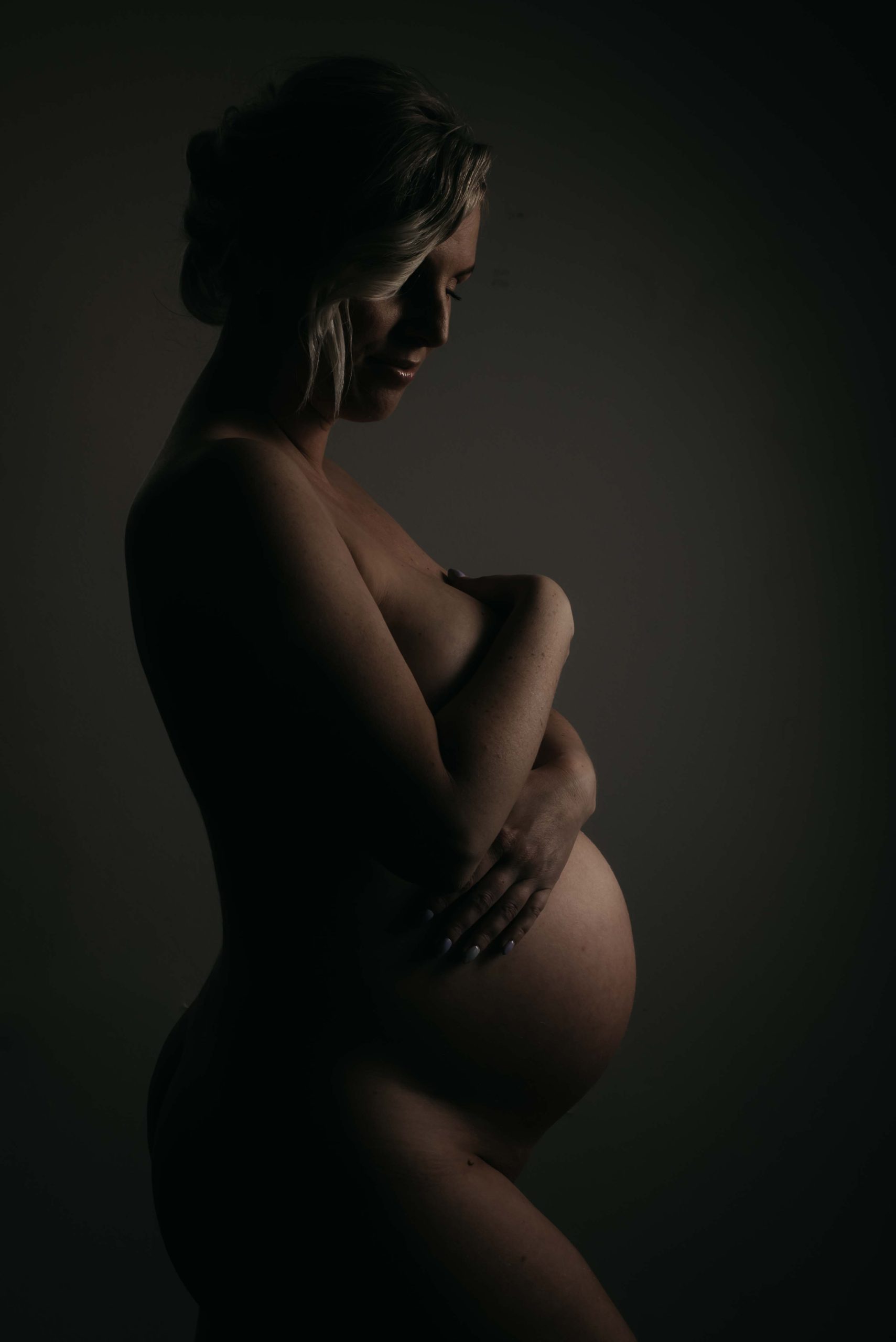 nøgen gravid kvinde krammer sin mave