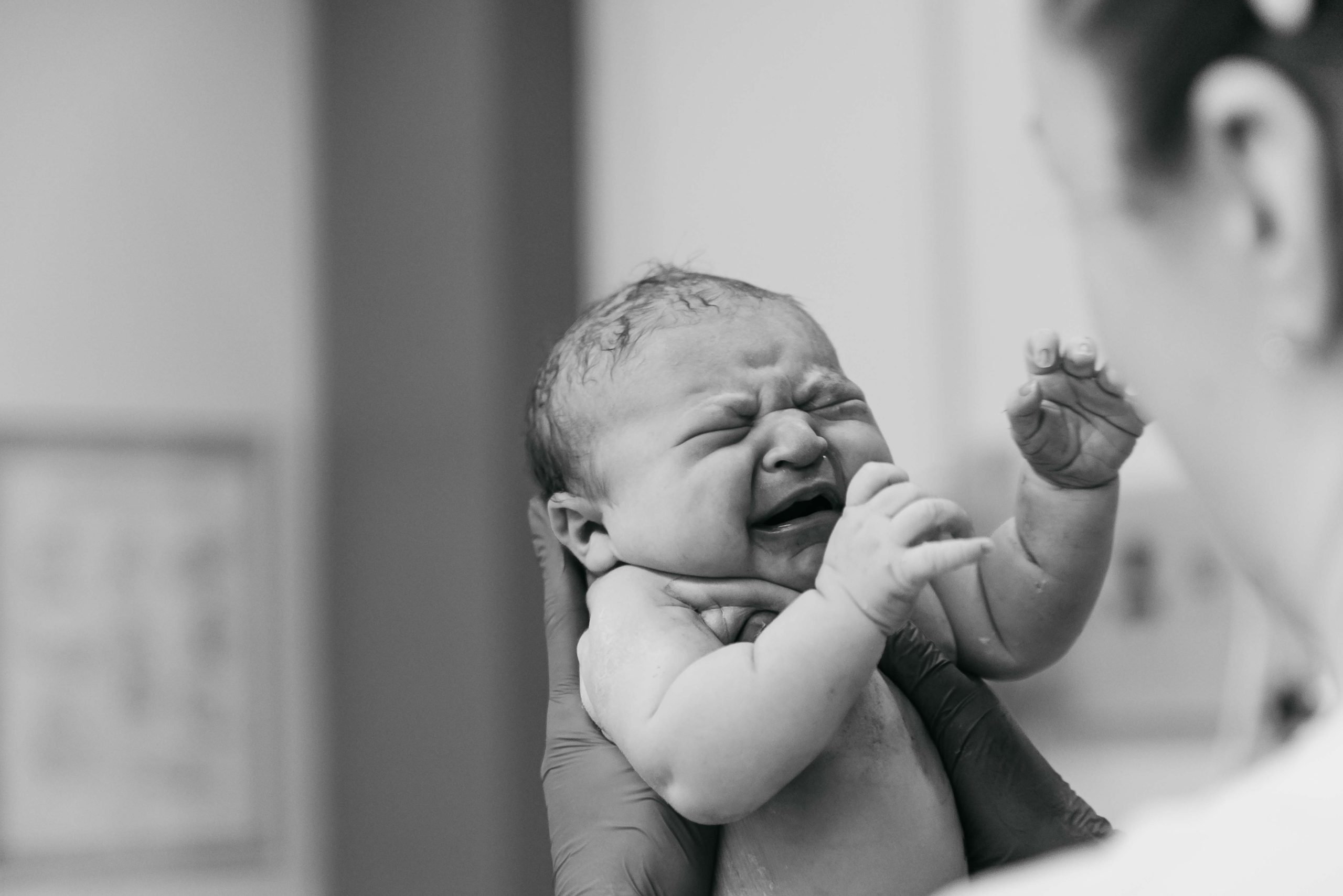 nyfødt lille pige løftes af sygeplejerske