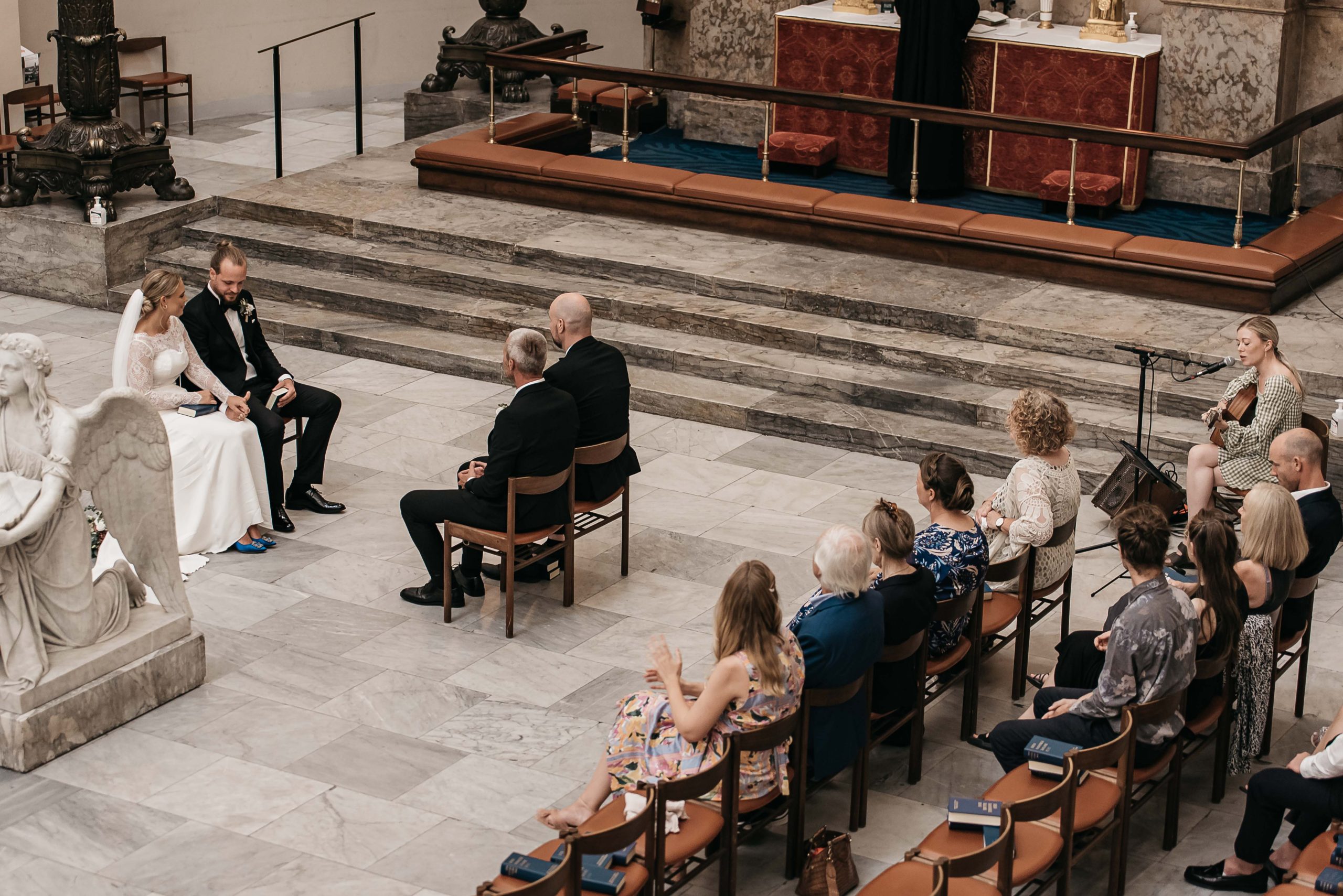 brudpar og gæster sidder i Vor Frue Kirke og hører på violinspil