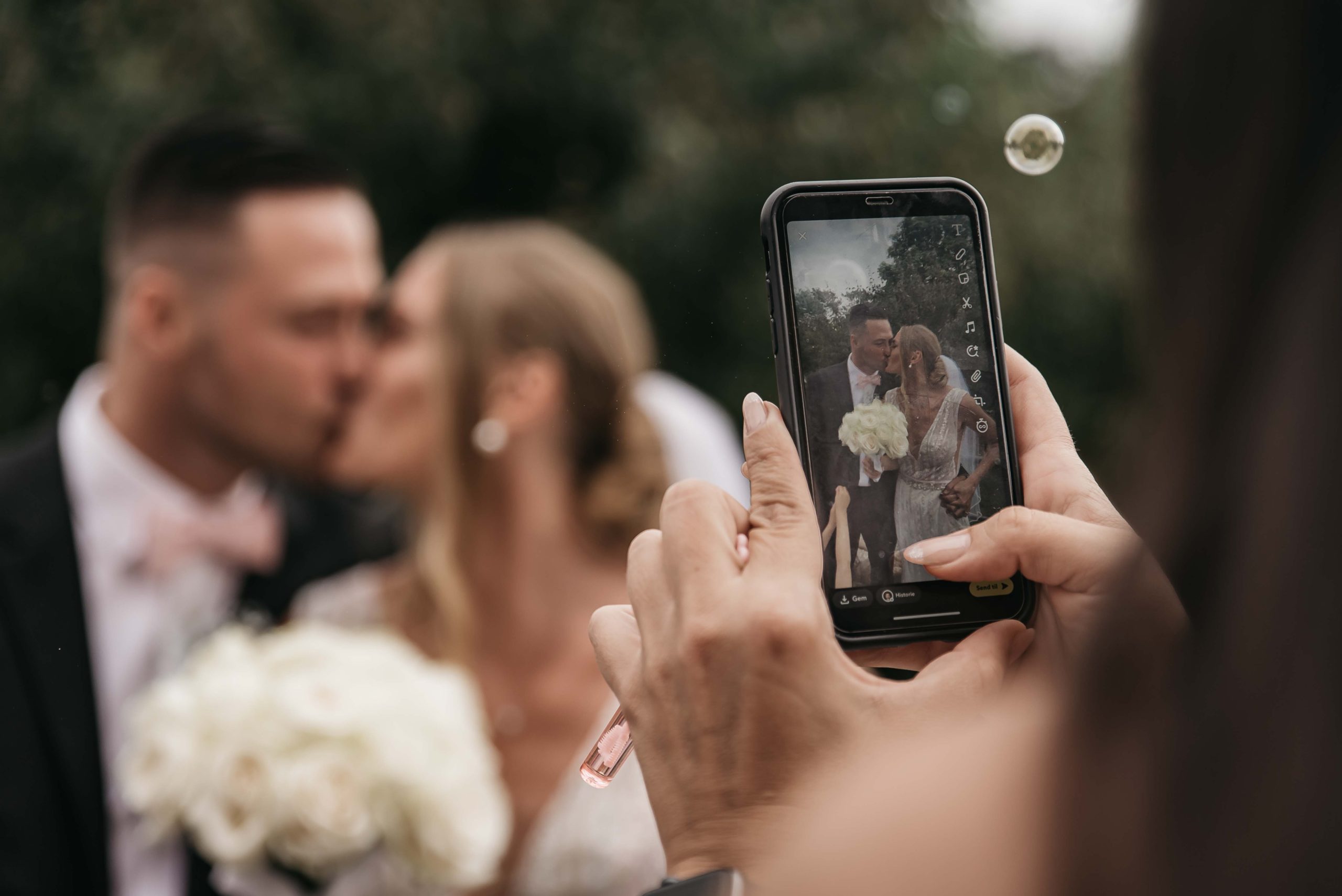 en gæst tager billeder af brudeparret med sin telefon